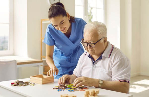 dementia-caregiver-assisting-elderly-man-puzzle