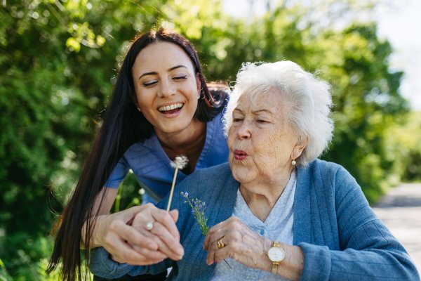 dementia-caregiver-elderly-woman-blowing-dandelion