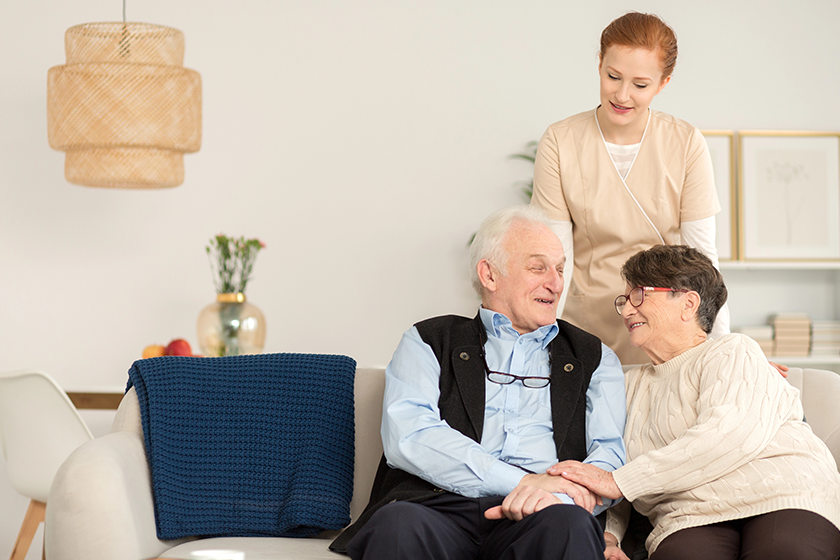 Happy senior couple sitting on a sofa and their nurse